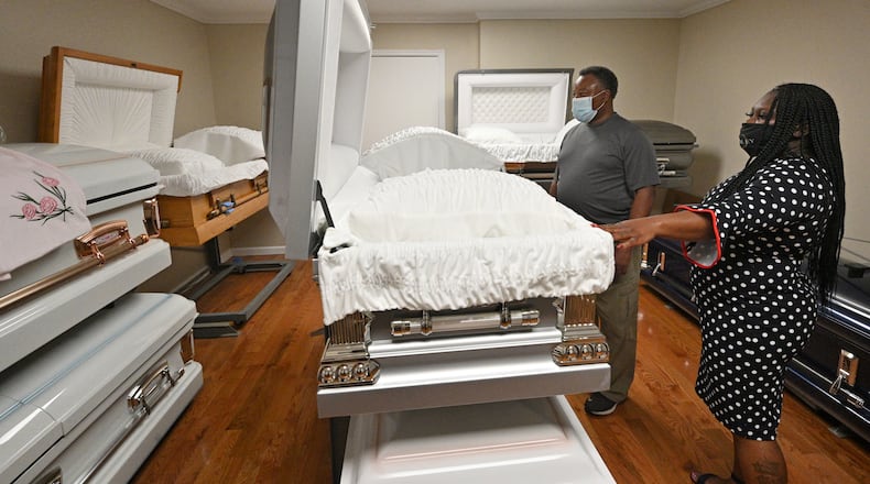 Carol Plummer Wright helps a client in the casket show room at Dudley Funeral Home in Dublin in March. The funeral home handled a high number of funerals over the last year. Now some of those families may be eligible for federal relief. (Hyosub Shin / Hyosub.Shin@ajc.com)