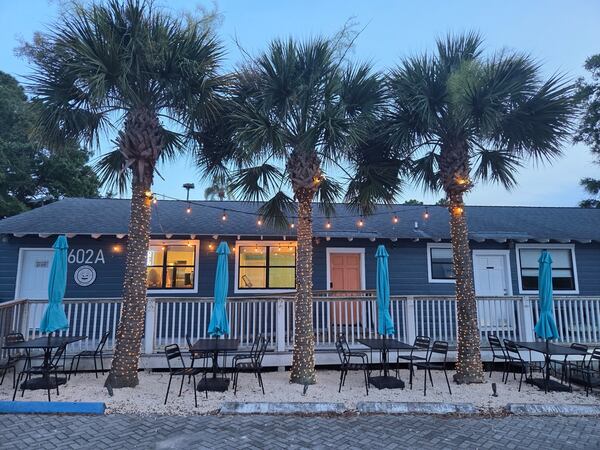 The exterior of beach coffee shop with three palmetto trees in front of it.