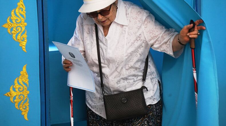 A woman leaves a booth to cast her vote at a polling station during early parliamentary elections in Almaty, Kazakhstan, Sunday, Aug. 23, 2026. (AP Photo/Vladimir Tretyakov)