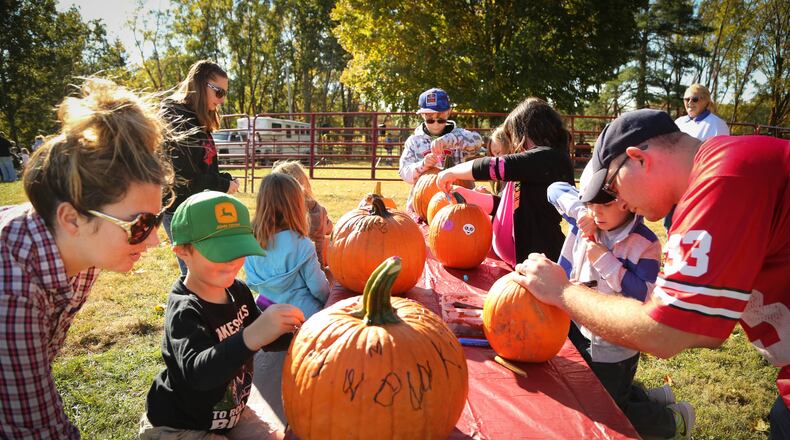 Kids and parents decorate pumpkins at the Fall Farm Fest at Lost Creek Reserve Saturday. The Miami County Park District hosts their biggest event of the year at the historic Knoop Homestead for thousands of people who attend the two day festival celebrating the agricultural heritage of Miami County. JIM WITMER/STAFF