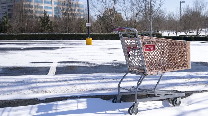 Some shopping gets put off because of the storm and just gets postponed until later. An abandoned shopping cart rests in the snow near shopping center in Alpharetta. ALYSSA POINTER/ALYSSA.POINTER@AJC.COM