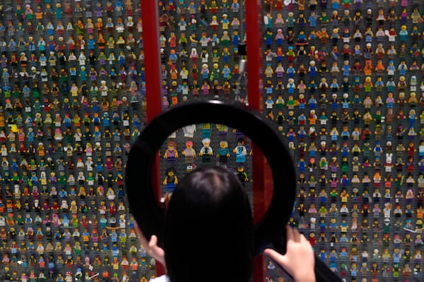 A child uses a magnifying glass to look at Lego characters at the hotel in Legoland Shanghai a day before it opens to the public in Shanghai, China, Friday, July 4, 2025. (AP Photo/Ng Han Guan)