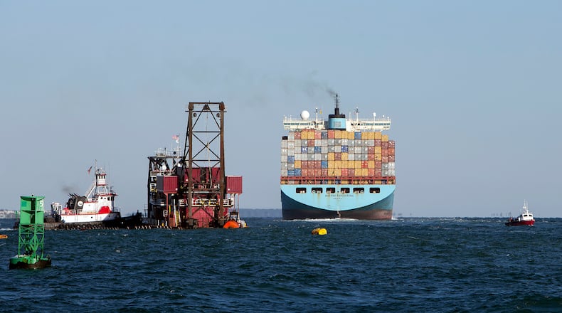 A container-laden cargo ship passes a dredging vessel working to deepen the Savannah River channel off Tybee Island. (Stephen B. Morton/AP 2015)