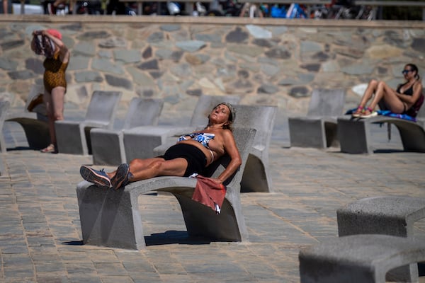 FILE - People sunbathe on a promenade in Barcelona, Spain, Wednesday, July 24, 2024. Several regions of Spain are under alert for high temperatures. (AP Photo/Emilio Morenatti,File)