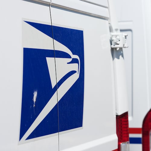 Delivery vans bearing the logo sit during a protest staged as part of a countrywide National Day of Action Tuesday, July 28, 2026, outside the main United States Postal Service headquarters in northeast Denver. (AP Photo/David Zalubowski)