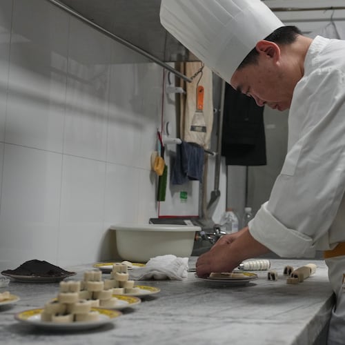 Chef Zhou Tong makes the minced pork pancake at Fangshan Restaurant inside Beihai Park in Beijing on July 23, 2026. (AP Photo/Andy Wong)