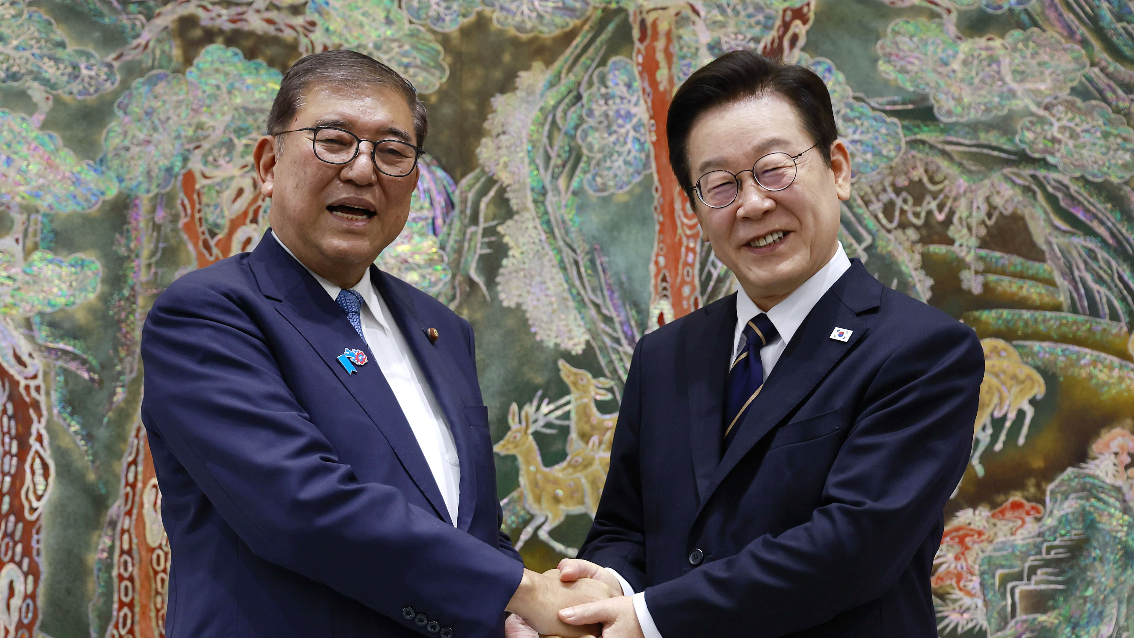 South Korean President Lee Jae Myung, right, shakes hands with Japanese Prime Minister Shigeru Ishiba, left, during a meeting in Busan, South Korea, Tuesday, Sept. 30, 2025. (Yonhap via AP)