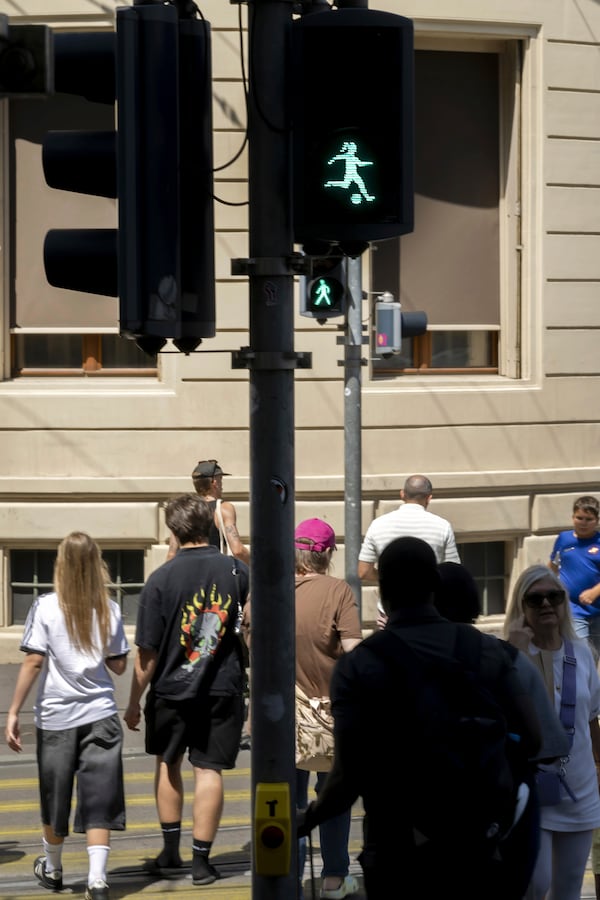 People walk by a pedestrian light with a woman kicking a soccer ball in Basel, Switzerland, to honor the Women's European Championship being hosted by the country, Friday, July 4, 2025. (Georgios Kefalas/Keystone via AP)