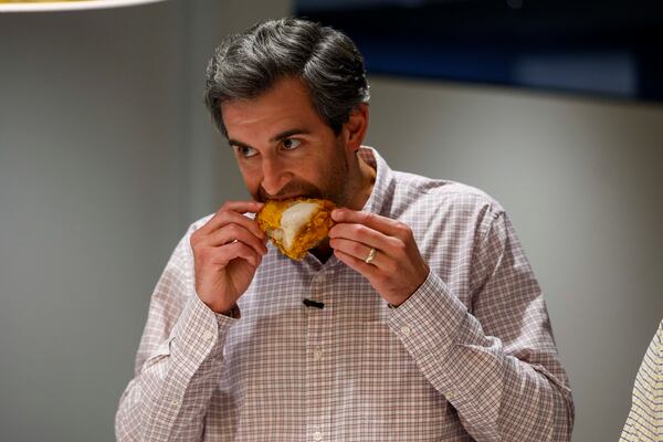 Climate + Environment Reporter Drew Kann takes a bite of fried chicken during a fried chicken contest on Tuesday, Aug. 25, 2026, at the AJC office in Midtown to determine Atlanta’s best fried chicken. (Miguel Martinez/AJC)