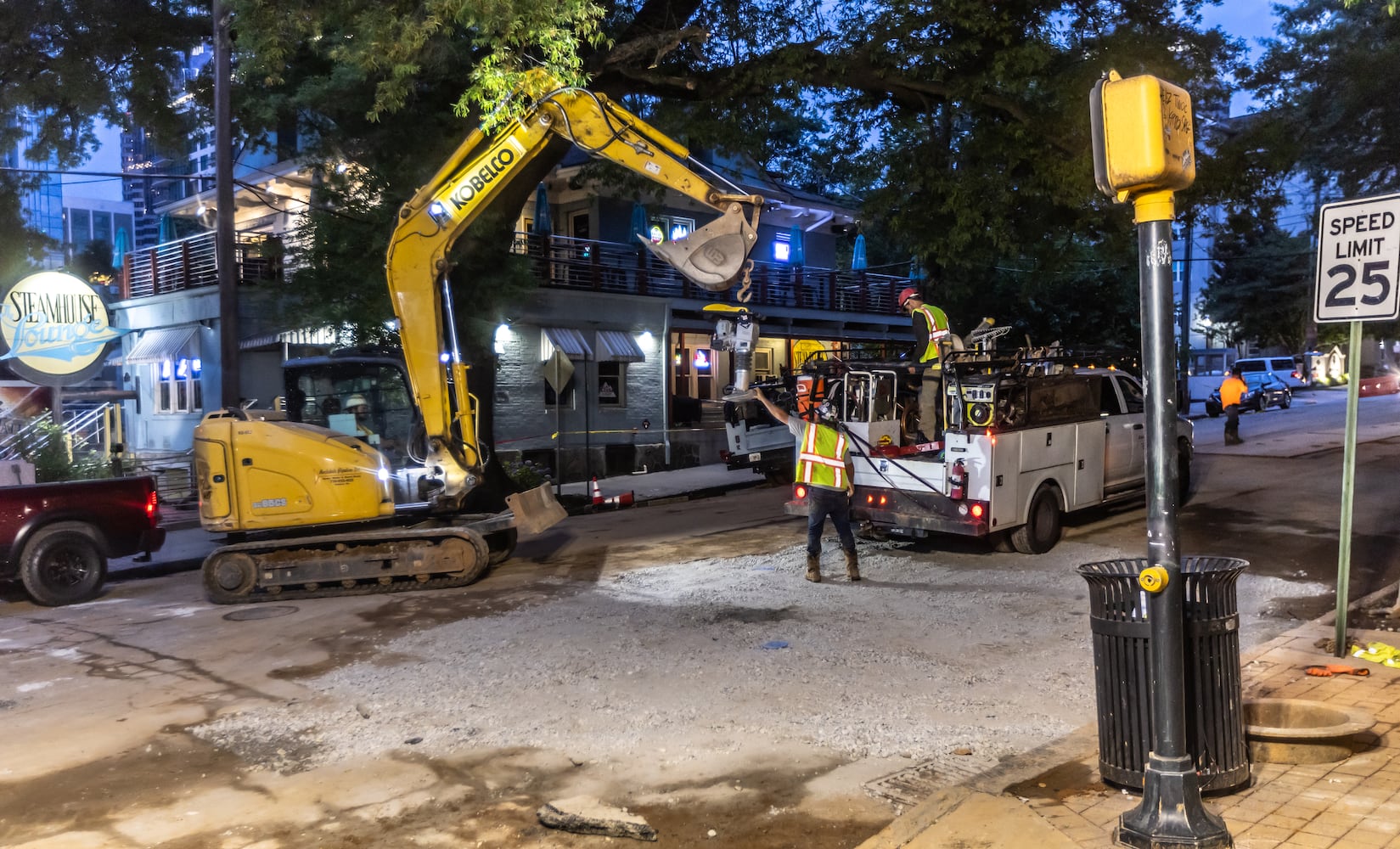 Workers continued to put the finishing touches on the filled in water main hole Wednesday morning, June 5, 2024 following the city’s announcement that water had been restored following the break on West Peachtree Street and 11th Street. The city said the system was being brought back online slowly to “allow system pressures to build.” (John Spink/AJC)