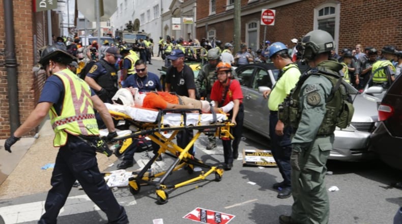 Rescue personnel help injured people after a car ran into a large group of protesters after an white nationalist rally in Charlottesville, Va., Saturday, Aug. 12, 2017. The nationalists were holding the rally to protest plans by the city of Charlottesville to remove a statue of Confederate Gen. Robert E. Lee. There were several hundred protesters marching in a long line when the car drove into a group of them. (AP Photo/Steve Helber)