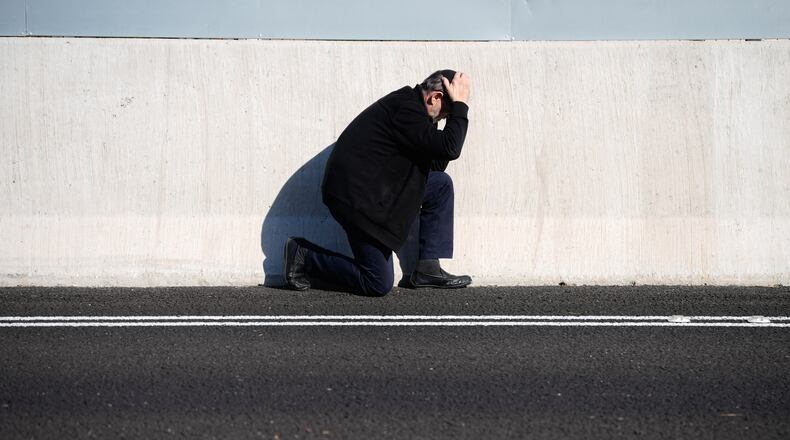 A man takes cover by the side of the road as an air raid sirens warn of incoming Iranian missile strikes in Tel Aviv, Israel, March 17, 2026. (AP Photo/Ohad Zwigenberg)