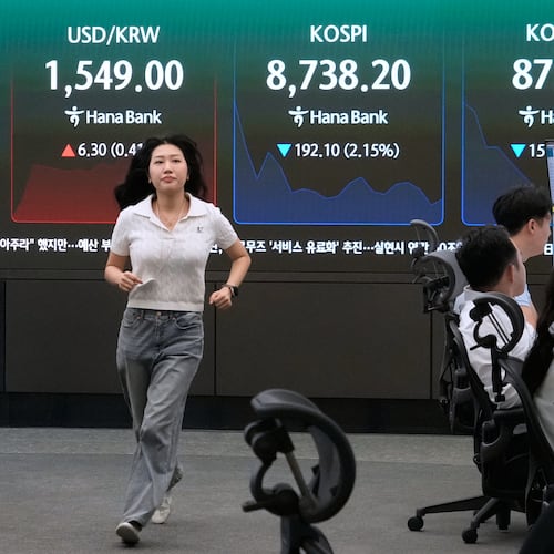 A currency trader passes by a screen showing the Korea Composite Stock Price Index (KOSPI) and the foreign exchange rate between U.S. dollar and South Korean won at the foreign exchange dealing room of the Hana Bank headquarters in Seoul, South Korea, Friday, June 26, 2026. (AP Photo/Ahn Young-joon)