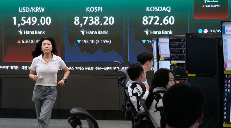 A currency trader passes by a screen showing the Korea Composite Stock Price Index (KOSPI) and the foreign exchange rate between U.S. dollar and South Korean won at the foreign exchange dealing room of the Hana Bank headquarters in Seoul, South Korea, Friday, June 26, 2026. (AP Photo/Ahn Young-joon)