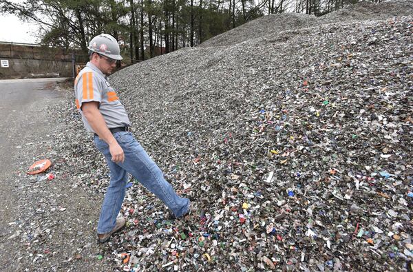 Tom Fletcher, plant manger, shows mixed recyclable materials at Strategic Materials recycling facility in College Park. (HYOSUB SHIN / HSHIN@AJC.COM)