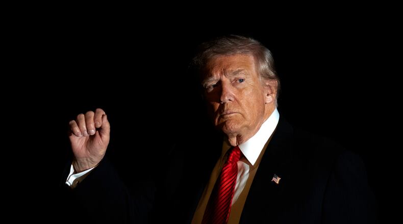 FILE - President Donald Trump is illuminated by a camera flash as he gestures while walking across the South Lawn of the White House, Nov. 2, 2025, in Washington, after returning from a trip to Florida. (AP Photo/Mark Schiefelbein, File)