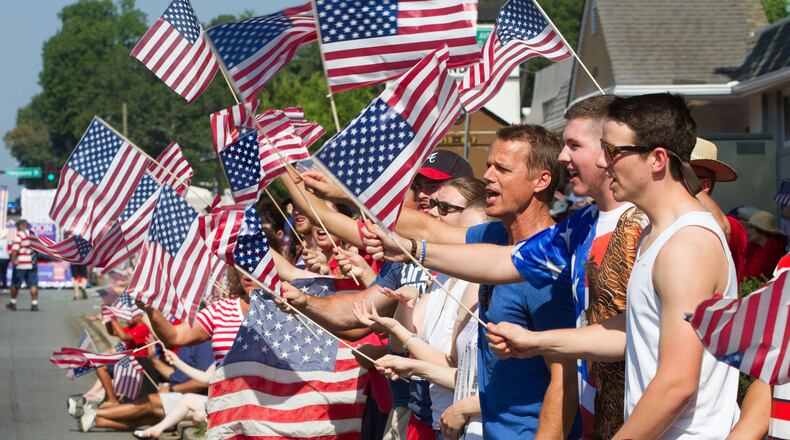 Spectators wave their flags as the Marietta Freedom Parade makes its way down Roswell Street on Tuesday, July 4, 2016, In Marietta, GA. An estimated 30,000 spectators turned out for the parade. STEVE SCHAEFER / SPECIAL TO THE AJC