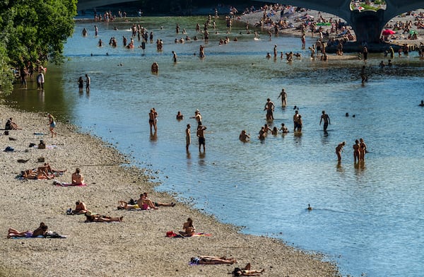 People enjoy the waters of the Isar around the Kabelsteg in Munich, Germany, Sunday June 29, 2025. (Peter Kneffel/dpa via AP)