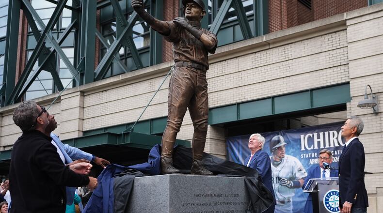Former Seattle Mariners Edgar Martinez, left, and Ken Griffey Jr., second from left, look on with right fielder Ichiro Suzuki, right, at the broken bat of Ichiro's statue during its unveiling outside of T-Mobile Park, Friday, April 10, 2026, in Seattle. (AP Photo/Lindsey Wasson)