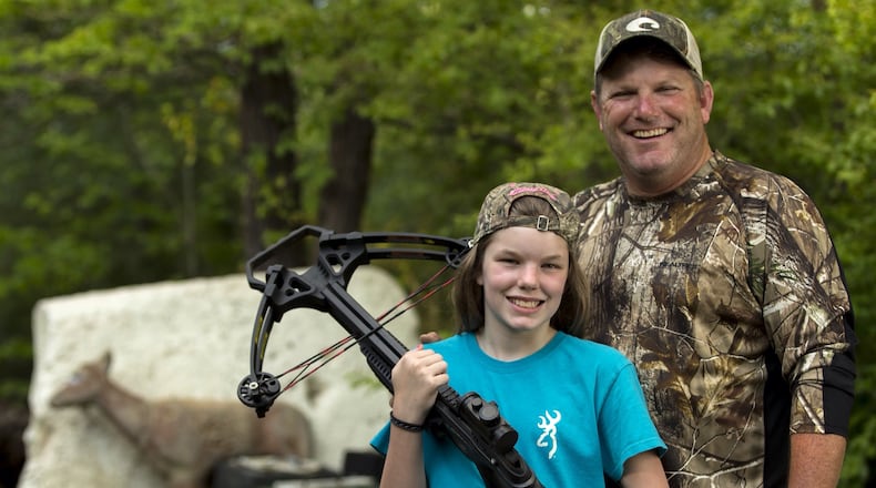 Stormy Smith with her dad, Todd, and her crossbow. Smith took Stormy his Bartow County hunting camp when she was 10 and was surprised that she became interested in hunting herself. Last year, at 11, she shot and killed her first doe with a crossbow. She's now 12 and is hoping to shoot a buck this fall. Ben Gray / bgray@ajc.com