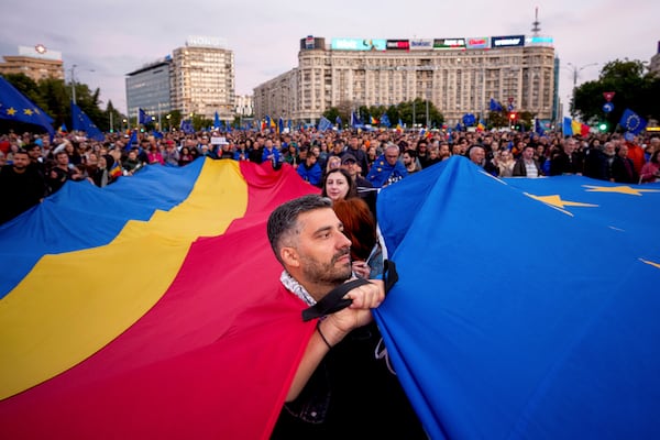 FILE - Demonstrators hold large Romanian and European Union flags during a pro-EU rally ahead of the second round of the presidential election redo in Bucharest, Romania, Friday, May 9, 2025. (AP Photo/Andreea Alexandru, File)