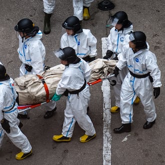 Police remove what appears to be a body bag from the site of a deadly Wednesday fire at Wang Fuk Court, a residential estate in the Tai Po district of Hong Kong's New Territories on Sunday, Nov. 30, 2025. (AP Photo/Chan Long Hei)