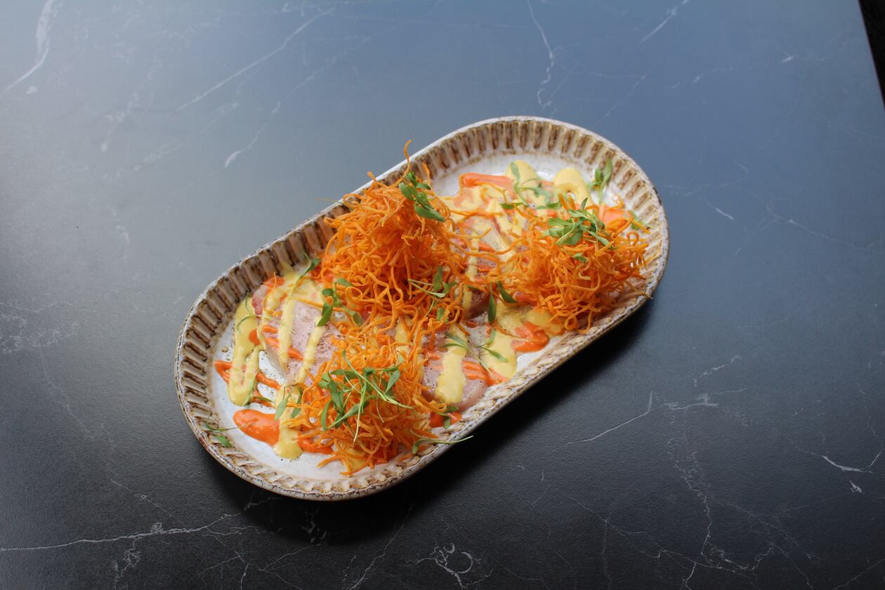 Hamachi tiradito has been on the menu of Fogon and Lions since they opened. Thinly sliced hamachi is arranged on sauces made from aji rojo and aji amarillo peppers and topped with fried sweet potato threads. (Courtesy of Fogon and Lions)