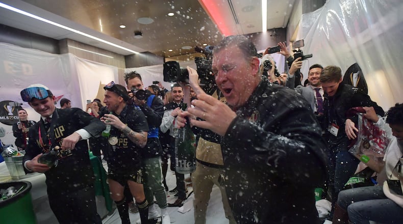 Atlanta United head coach Gerardo Martino gets soaked with beers as players celebrate in their locker room after Atlanta United beat the Portland Timbers Saturday, Dec. 8, 2018, for the MLS Cup championship.