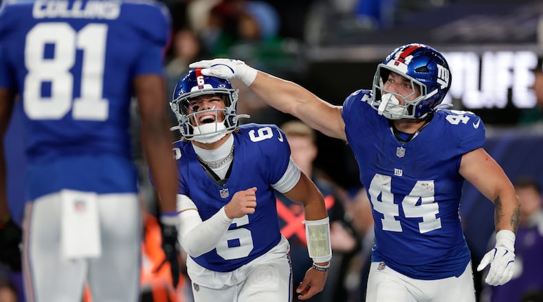New York Giants' Jaxson Dart, center, and Cam Skattebo celebrate after a touchdown during the first half of an NFL football game against the Philadelphia Eagles Thursday, Oct. 9, 2025, in East Rutherford, N.J. (AP Photo/Adam Hunger)