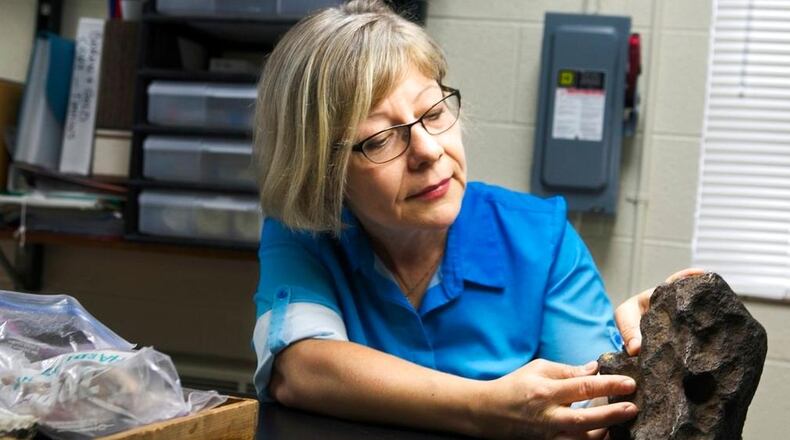 In this Sept. 14, 2018 photo provided by Central Michigan University, Monaliza Sirbescu, a geology faculty member in earth and atmospheric sciences shows off a 22-plus pound meteorite that was being used as a doorstop on a farm in Edmore, Mich. The iron and nickel meteorite is the sixth largest meteorite found in Michigan, according to the Smithsonian Museum and Central Michigan University. Owner David Mazurek said the meteorite came with a barn he bought in 1988 in Edmore. He says the farmer who sold him the property told him it landed in his backyard in the 1930s. (Mackenzie Brockman/Central Michigan University via AP)