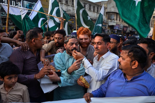 People share cake as they celebrates following India and Pakistan have reached a ceasefire deal, during a demonstration, in Hyderabad, Pakistan, Saturday, May 10, 2025. (AP Photo/Pervez Masih)