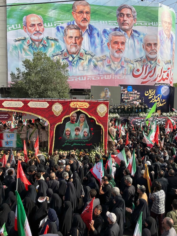People mourn over the flag-draped coffins of Iranian army generals, nuclear scientists and their family members who were killed in Israeli strikes, during a funeral ceremony in Tehran. Iran, Saturday, June 28, 2025. (AP Photo/Vahid Salemi)