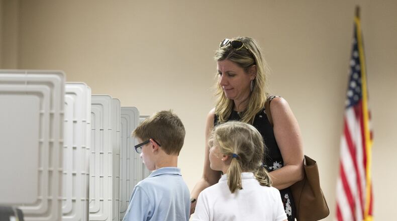 Dunwoody resident Kari Downing and her children Reagan and Thomas stand at a voting machine April 18 at the DeKalb County Public Library in Dunwoody during voting in the highly contested 6th Congressional District race. (DAVID BARNES / DAVID.BARNES@AJC.COM)