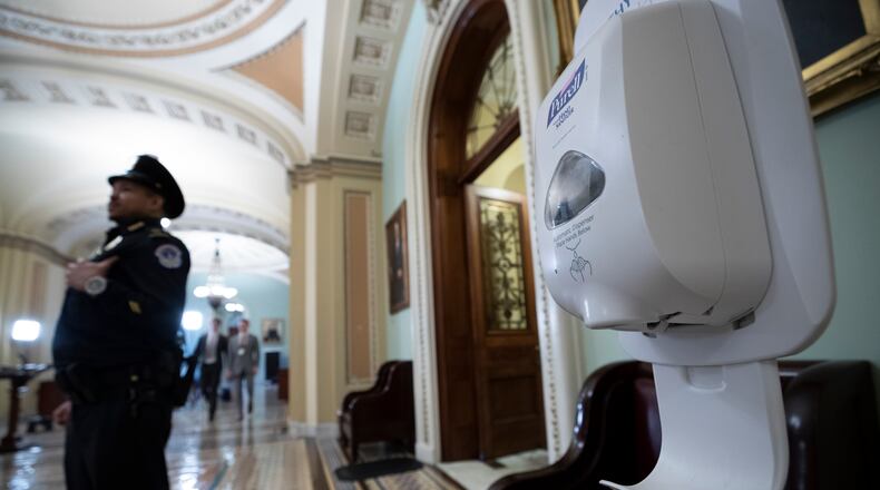 A hand sanitizer dispenser is placed just outside the floor of the U.S. Senate chamber after concerns about the coronavirus, Tuesday, March 3, 2020 in Washington. (AP Photo/Alex Brandon)