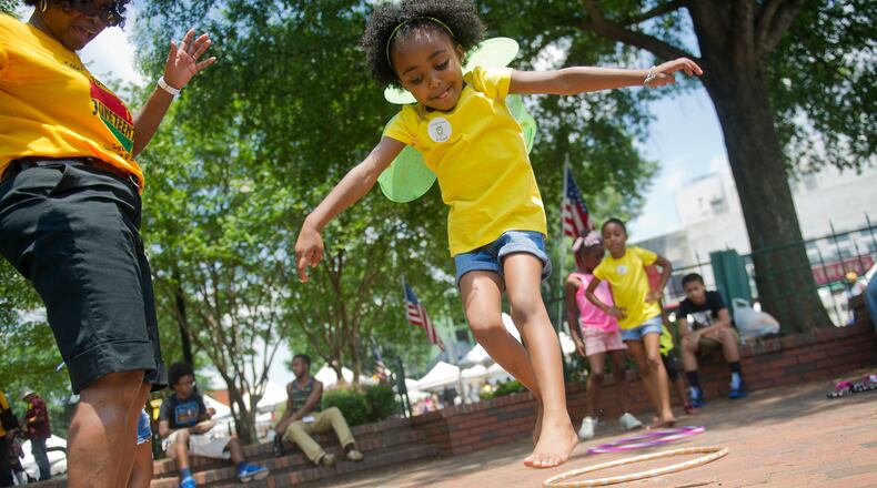 Nia Caudle (center) jumps into the center of a hoop as she plays games during the Cobb NAACP Juneteenth Celebration in Marietta Square. JONATHAN PHILLIPS / SPECIAL