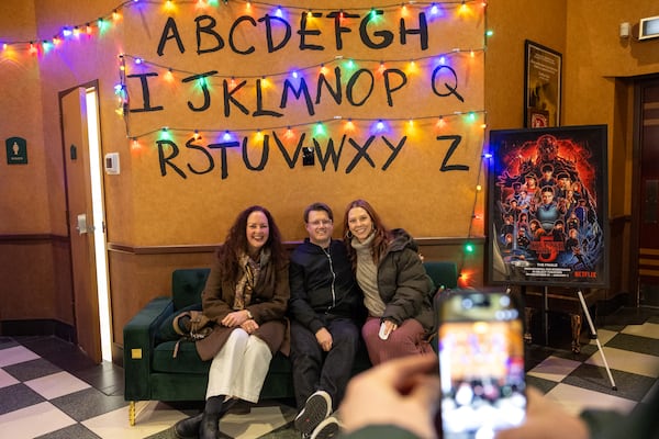 Christina Wolverton (from left), Will Pugh and Caitlin Pugh pose in front of a “Stranger Things”-themed backdrop before the series finale at the Tara Theatre on Wednesday, Dec. 31, 2025, in Atlanta. (Arvin Temkar/AJC)