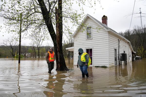Abner Wagers, right, and Brayden Baker, both with the Monterey Volunteer Fire Department, walk in the rising waters of the Kentucky River near a flooded home in Monterey, Ky., Sunday, April 6, 2025. (AP Photo/Carolyn Kaster)