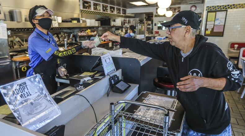 Waffle House’s Miss D (left) takes money from Daniel Bahena (right) after he and a guest dined in on Monday at a location on Clairmont Road in Brookhaven. Some restaurants in metro Atlanta began to reopen dining rooms as certain restrictions related to the coronavirus pandemic were lifted. JOHN SPINK/JSPINK@AJC.COM