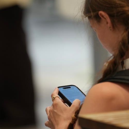 A teenager looks at her mobile phone in London, Monday, June 15, 2026. (AP Photo/Kin Cheung)