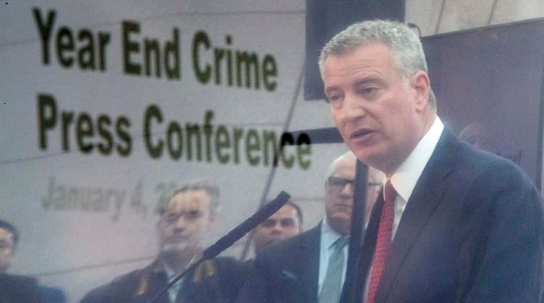 New York City Mayor Bill de Blasio is seen reflected on a television monitor as he speaks during a news conference, Wednesday, Jan. 4, 2017, in New York. New York City recorded its fewest number of shootings last year and narrowly missed setting a record low for homicides. According to data released Wednesday, the city had 335 homicides in 2016. The city's record low was 333 in 2014. Police officials reported 998 shooting incidents in 2016. Overall crime was also at its lowest.(AP Photo/Mary Altaffer)