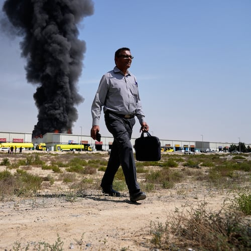 FILE - A man walks away after watching a black plume of smoke rise from a warehouse in the industrial area of Sharjah City, United Arab Emirates, March 1, 2026, following reports of Iranian strikes in Dubai. (AP Photo/Altaf Qadri, File)