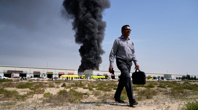 FILE - A man walks away after watching a black plume of smoke rise from a warehouse in the industrial area of Sharjah City, United Arab Emirates, March 1, 2026, following reports of Iranian strikes in Dubai. (AP Photo/Altaf Qadri, File)