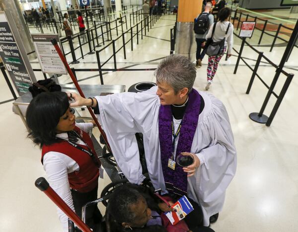The Episcopal Chaplain to Hartsfield-Jackson Atlanta International Airport, Rev. Dr. Donna Mote (right) dispenses ashes to Prospect Airport Service employee Neisha Ogletree (left) in front of the main security checkpoint in the domestic terminal Wednesday, March 1, 2017. (AJC FILE)