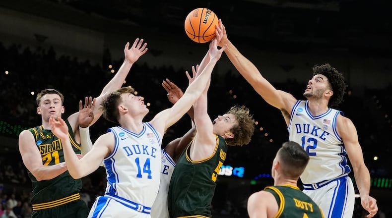 Duke's Cameron Boozer (12) and Nikolas Khamenia (14) battle for the ball with Siena's Riley Mulvey (55), Brendan Coyle (21) and Gavin Doty (4) during the first half in the first round of the NCAA college basketball tournament, Thursday, March 19, 2026, in Greenville, S.C. (AP Photo/Brynn Anderson)