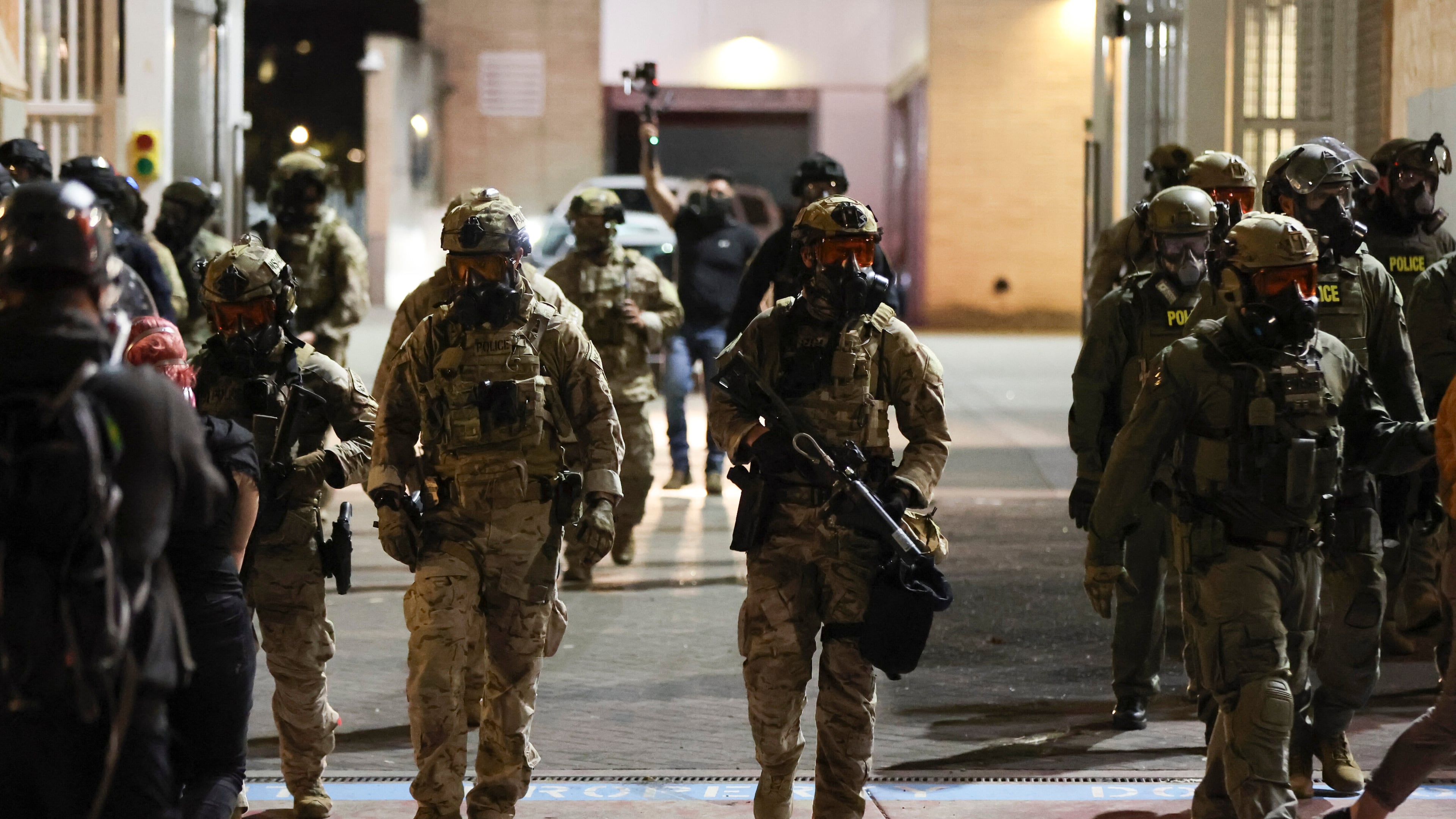 Federal agents walk into the street as people protest outside a U.S. Immigration and Customs Enforcement facility in Portland, Oregon, Friday, Oct. 3, 2025. (AP Photo/Amanda Loman)