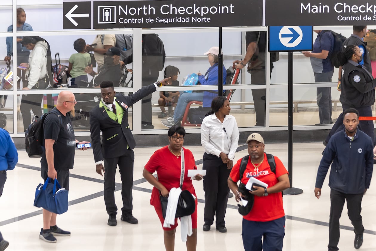 Airport customer service employee Ebou John (center left) helps a traveler with directions at Hartsfield-Jackson Atlanta International Airport in May 2024. (John Spink/AJC)