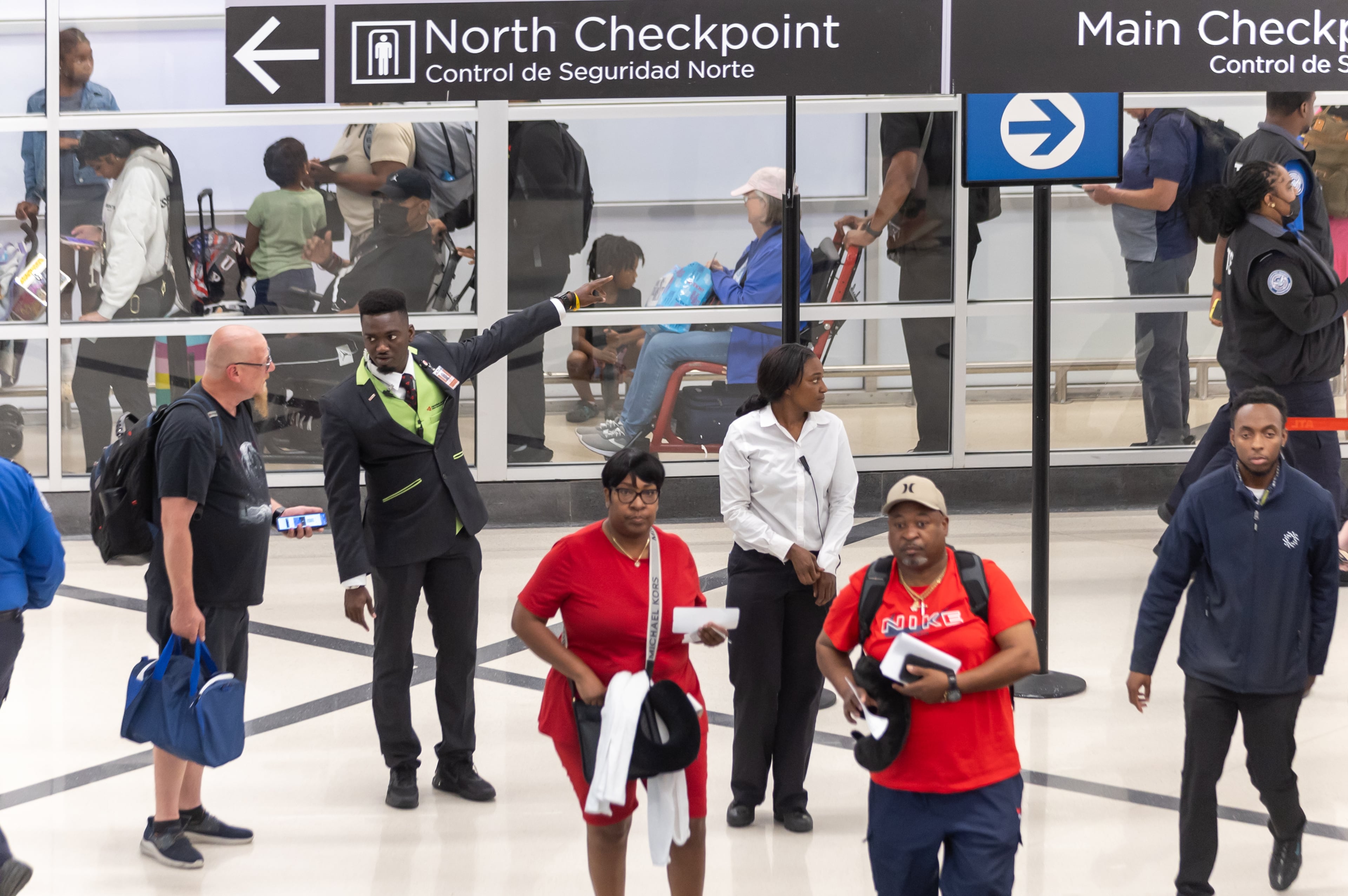 Airport customer service employee Ebou John (center left) helps a traveler with directions at Hartsfield-Jackson Atlanta International Airport in May 2024. (John Spink/AJC)