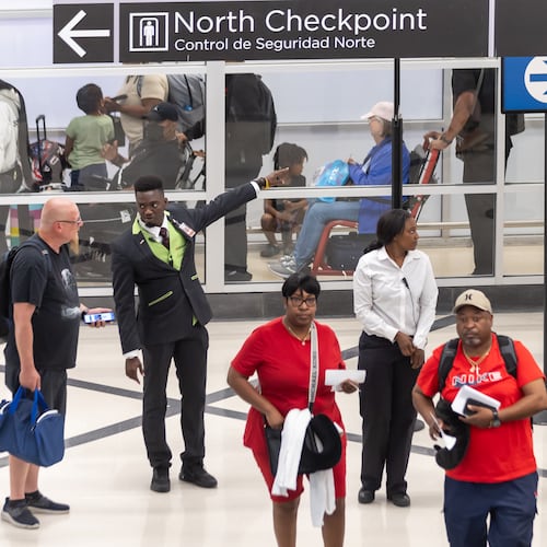 Airport customer service employee Ebou John (center left) helps a traveler with directions at Hartsfield-Jackson Atlanta International Airport in May 2024. (John Spink/AJC)