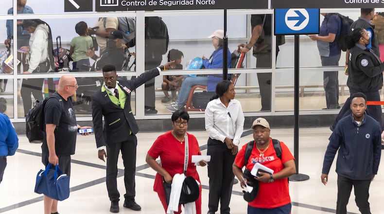 Airport customer service's Ebou John (center-left) helps a traveler with directions. Travelers swelled Atlanta's Hartsfield-Jackson International Airport on Friday, May 24, 2024. (John Spink/AJC)