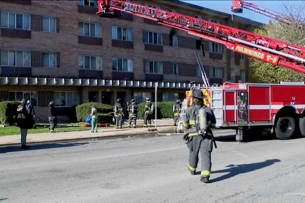 This image taken from video provided by WISN shows firefighters working at the site of an apartment building fire in Milwaukee, Wis., Sunday, May 11, 2025. (WISN via AP)